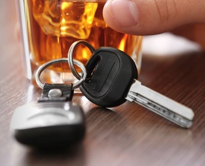 A set of car keys with a drink in the background. 