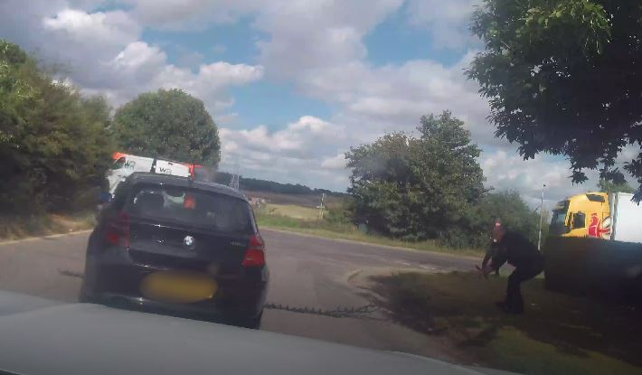 A black BMW car travelling over a stinger device. 