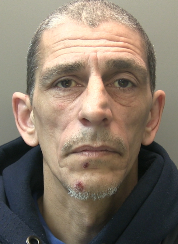 Man faces the camera with short, greying hair and small amount of similar colour facial hair. He's wearing a black hoodie.. 