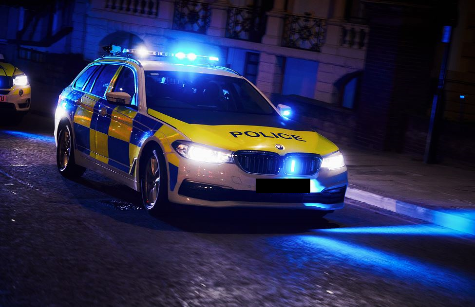 A marked patrol car parked in the dark with blue lights showing.