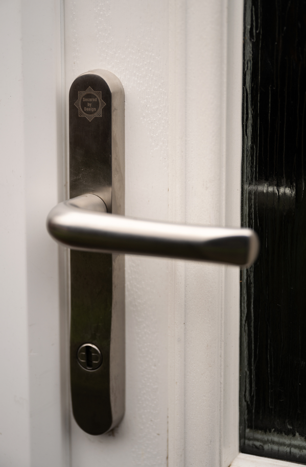 Close up of a silver door handle on a white doorframe