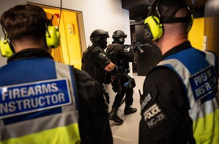 Police firearms instructors and officers in tactical gear during a training exercise.