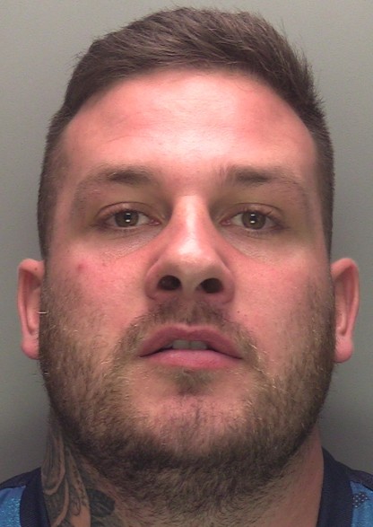 Man with mid-brown hair and similar facial hair faces the camera, has tattoos on his neck.