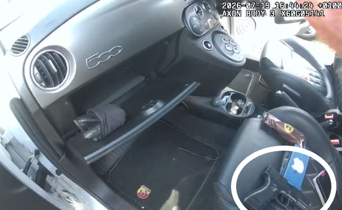 The inside of a Fiat 500 showing the passenger seat and glove box.  An imitation handgun is sat on the passenger seat. 