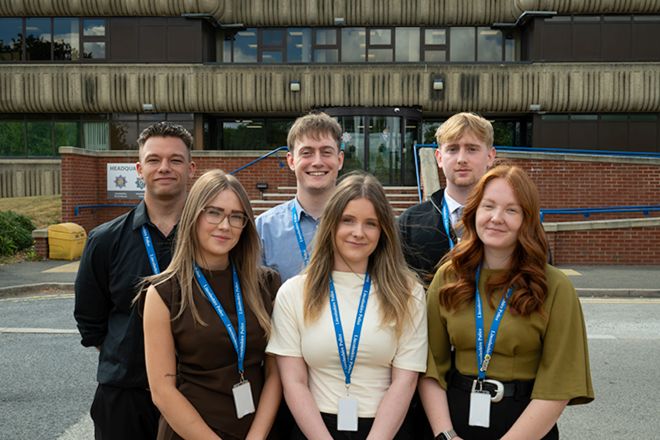 A group of six young adults wearing Lincolnshire Police lanyards standing outside the police  headquarters building. 