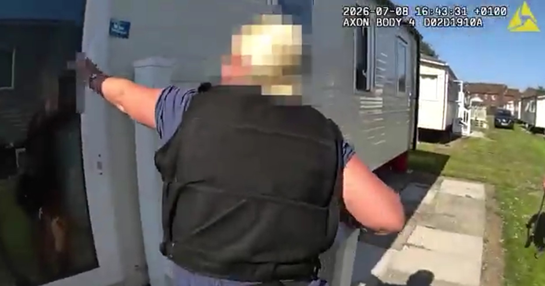 Officer in stab vest opening the door to a caravan