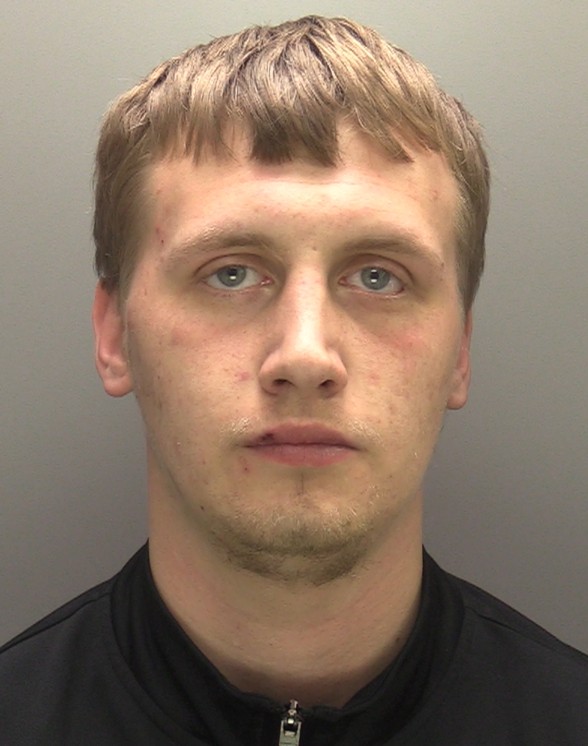 Man with dark blond hair, blue eyes, and stubble wearing a black zip up top