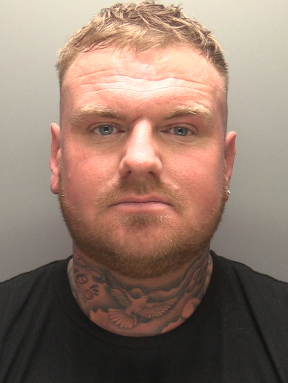 Man with red hair, neck tattoos and wearing a black t-shirt