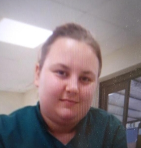 27-year-old missing Rhiannon. She is wearing a green top and is smiling at the camera.