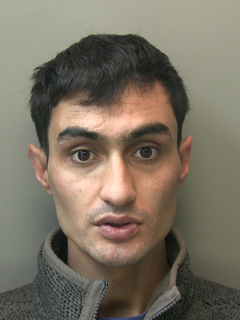 Custody shot of a man with dark hair, brown eyes, and a grey zip-up jacket.