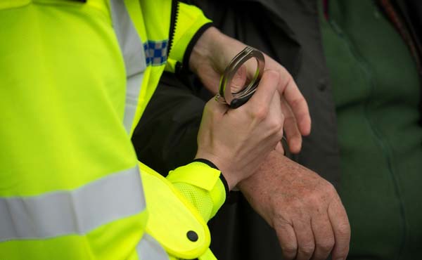 Officer putting handcuffs on a detained man 