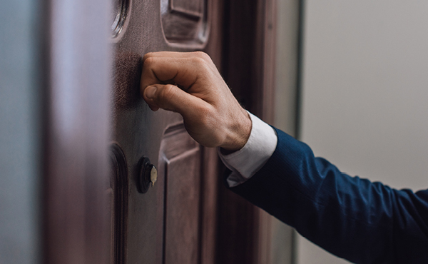 A hand knocks at a door. 