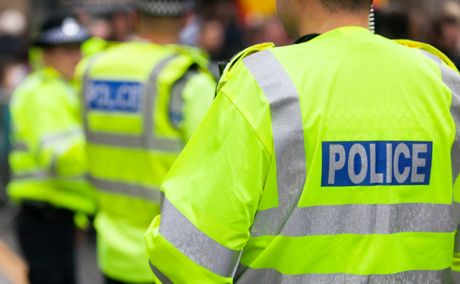 The backs of two police officers wearing high vis vests.