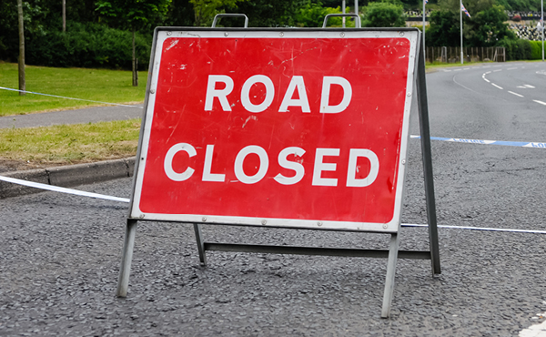 Red sign in the road with the words 'ROAD CLOSED' in white letters