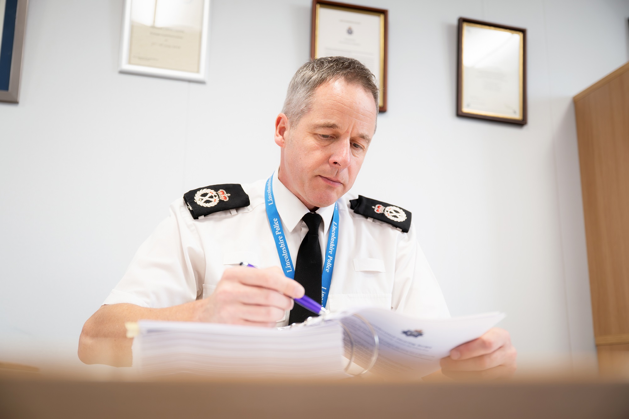 Chief Constable Paul Gibson sitting at a desk, reading papers